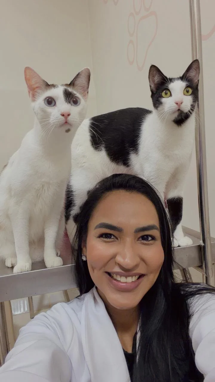 Dra. Thays Abbade sorrindo ao lado de dois gatos na clínica CPV Thays Abbade
